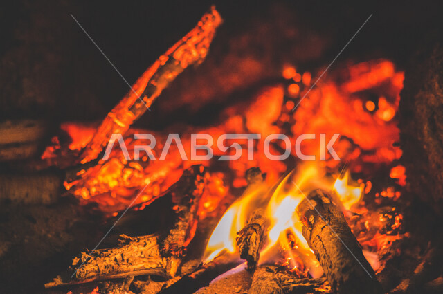 النيران المشتعلة  في الحطب ، اللهب الأحمر المشتعل في رحلة تخييم بالصحراء ، جمال الطبيعة في صحراء المملكة العربية السعودية ليلاً
