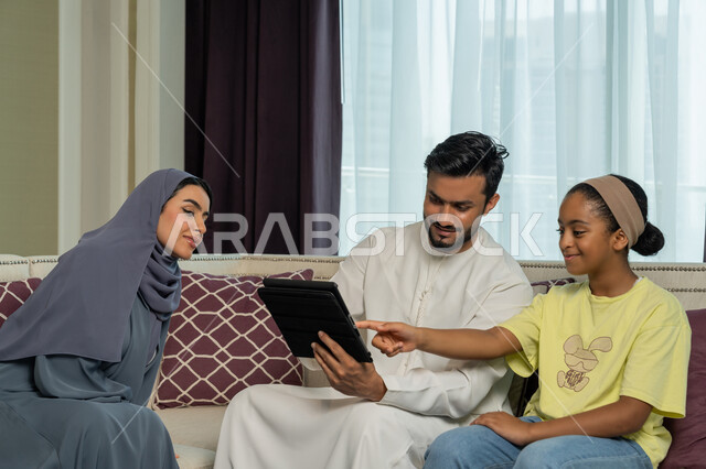 عائلة عربية خليجية اماراتية مبتسمة وسعيدة، استخدام الاجهزة والتقنيات الحديثة المتطورة, مشاهدة الافلام والقصص الالكترونية عبر جهاز التابليت اللوحي، الالفة والانسجام والمودة بين افراد الاسرة، قضاء وقت ممتع مع الاولاد