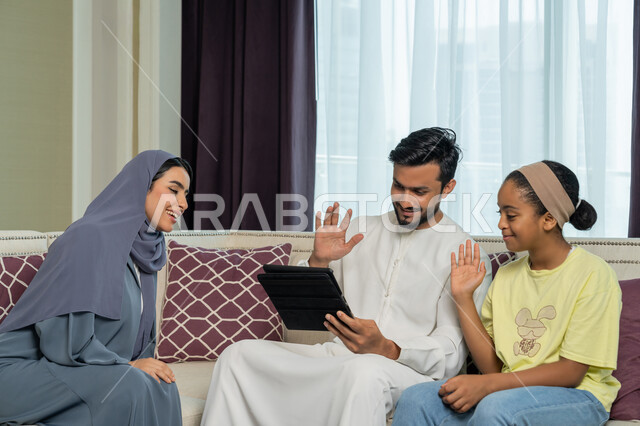 اجراء مكالمة فيديو عبر جهاز التابليت اللوحي، عائلة عربية خليجية اماراتية مبتسمة وسعيدة، استخدام الاجهزة والتقنيات الحديثة المتطورة, الالفة والانسجام والمودة بين افراد الاسرة، قضاء وقت ممتع مع الاولاد