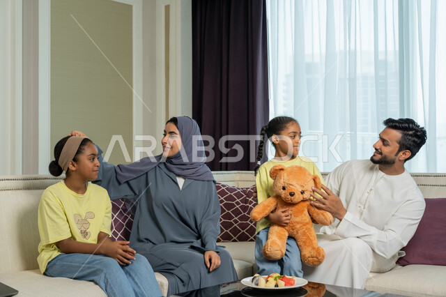 أسره عربيه خليجيه اماراتيه تجلس في غرفه المعيشه، مفهوم الأمان والإستقرار العائلي، أجواء عائليه سعيده مليئه بالحب والحنان، ايماءات الفرح والسعاده لقضاء أوقات ممتعه مع الأهل، الألفه والمحبه بين الآباء والابناء