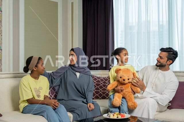 أجواء عائليه سعيده مليئه بالحب والحنان، مفهوم الأمان والإستقرار العائلي، أسره عربيه خليجيه اماراتيه تجلس في غرفه المعيشه، ايماءات الفرح والسعاده لقضاء أوقات ممتعه مع الأهل، الألفه والمحبه بين الآباء والابناء