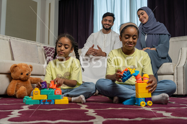 الالفة والانسجام والمودة بين افراد الاسرة، الاستمتاع بالعطلة الصيفية, قضاء وقت ممتع مع الاولاد، تنمية قدرات و مهارات الطفل, زوجان عربيان خليجيان اماراتيان ينظران الى ولديهما بتعابير الحب والسعادة, العاب تعليمية ترفيهية ممتعة, مساندة الأبناء و تشجيعهم