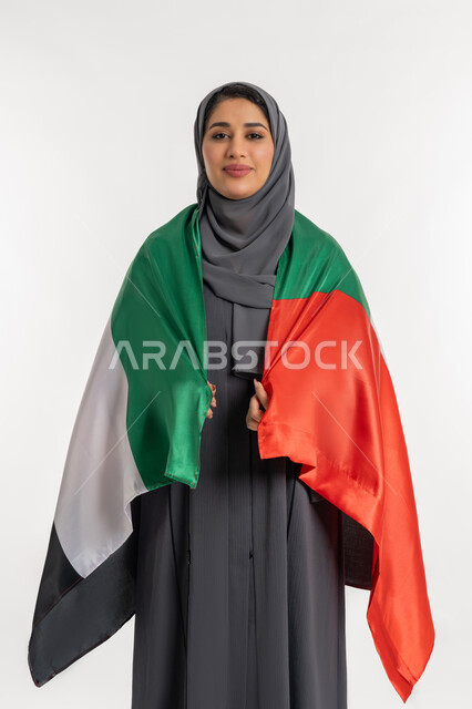 الاحتفال باليوم الوطني الإماراتي, الأعياد و المناسبات الوطنية, الاعتزاز والفخر بإنجازات الوطن، الاحتفال بالعيد الوطني الإماراتي 2 ديسمبر، بورتريه لامراة عربية خليجية إماراتية ترتدي العباءة تحمل علم الامارات على ظهرها، مفهوم الحب والانتماء للبلاد, خلفية بيضاء
