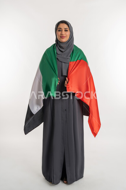 National holidays and occasions, pride in the achievements of the country, celebrating the UAE National Day on December 2, portrait of an Arab Gulf Emirati woman wearing an abaya carrying the UAE flag on her back, celebrating the UAE National Day, full body length, white background