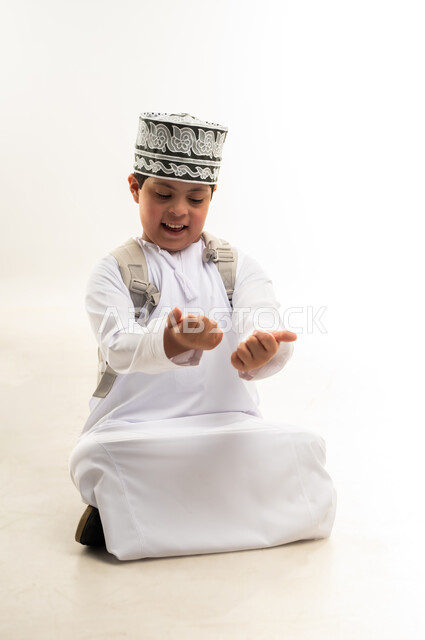 Learning mathematical operations, developing intellectual abilities in people with disabilities, portrait of an Arab Gulf Omani boy wearing a dishdasha and a turban, carrying a school backpack, doing mental arithmetic, quality of education in schools in the Sultanate of Oman, white background