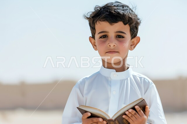 تنمية المهارات الفكرية لدى الأطفال منذ سن صغيرة، ولد عربي خليجي سعودي يرتدي الثوب التقليدي يقف ويحمل بيده كتاب، الاستمتاع بمراجعة الكتب المدرسية، قراءة القصص والروايات، اكتساب المعرفة والثقافة، قضاء الوقت بالتعلم الذاتي والاعتماد على النفس