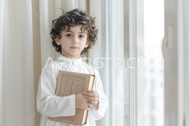 تنمية المهارات الفكرية لدى الأطفال منذ سن صغيرة، ولد عربي خليجي سعودي يرتدي الثوب التقليدي يقف ويحمل بيده كتاب، الاستمتاع بمراجعة الكتب المدرسية، قراءة القصص والروايات، اكتساب المعرفة والثقافة، قضاء الوقت بالتعلم الذاتي والاعتماد على النفس