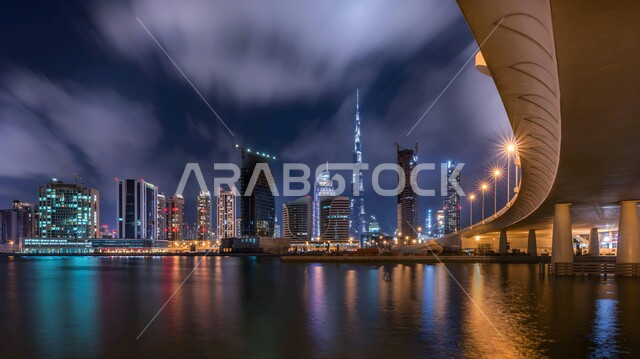Urban development and growth in the Emirate of Dubai, modern architectural arts and designs, building a developed civilized future, lighting facilities and high-rise commercial buildings at night, improving and developing the infrastructure of tourist cities, illuminated towers and skyscrapers at night in the United Arab Emirates