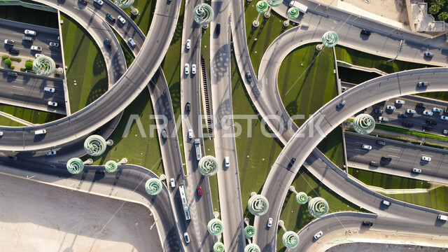 الاهتمام بزراعة النباتات الخضراء، حركة سير السيارات على الطريق السريع في مدينة الرياض، الفن الهندسي المعماري للمجسمات الفنية على شكل أشجار خضراء، الطرق المتقاطعة في دوار عرقة بالمملكة العربية السعودية، البنية التحتية المتطورة