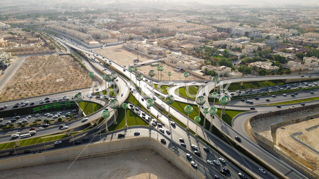 الاهتمام بزراعة النباتات الخضراء، حركة سير السيارات على الطريق السريع في مدينة الرياض، الفن الهندسي المعماري للمجسمات الفنية على شكل أشجار خضراء، الطرق المتقاطعة في دوار عرقة بالمملكة العربية السعودية، البنية التحتية المتطورة