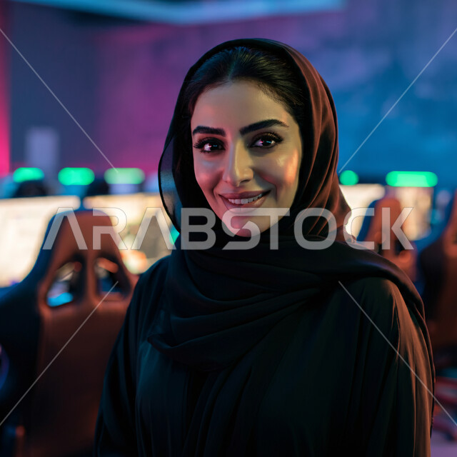 الأناقة والاهتمام بالمظهر الخارجي، أزياء محجبات عصرية راقية، قضاء اوقات ممتعة في المنزل، مفهوم الهدوء والاسترخاء والراحة، صورة مقربة لامرأة عربية خليجية سعودية مبتسمة ترتدي العباءة والحجاب تنظر الى الكاميرا بإيماءات السرور و الثقة بالنفس، الملامح العربية الأصيلة