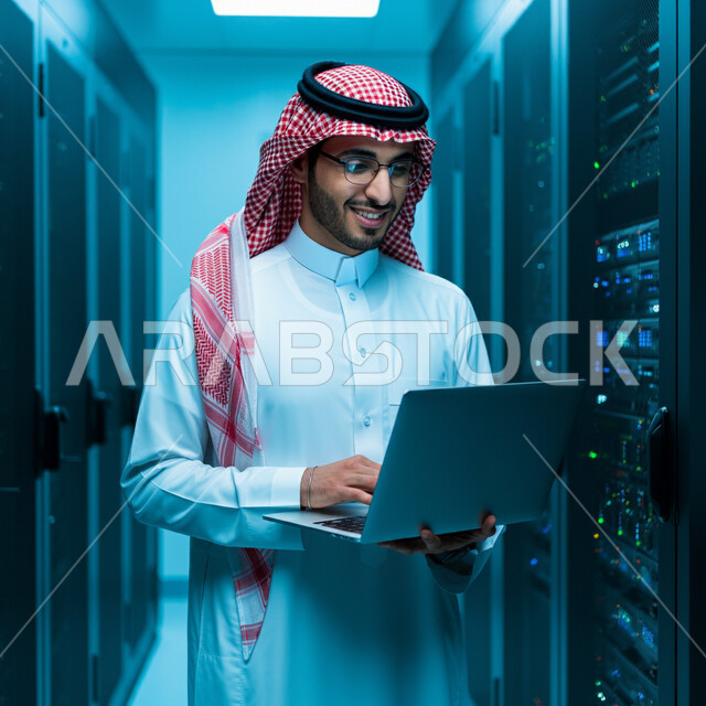 حفظ وتخزين المعلومات لمستخدمين المواقع، مفهوم تكنولوجيا التخزين السحابي، رجل عربي خليجي سعودي يرتدي الثوب التقليدي والشماغ يقوم بالإشراف وإدارة بيانات الداتا سنتر باستخدام الحاسوب المحمول، غرفة التحكم بالسيرفرات وخوادم الإنترنت العملاقة، أجهزة تقنية حديثة