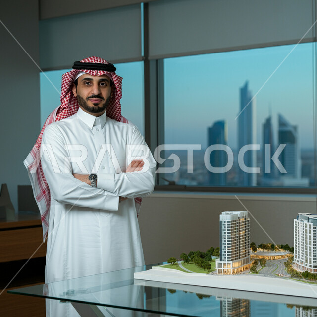 المهن والوظائف في المملكة العربية السعودية، نموذج بناء هندسي جديد لمشروع التخطيط العمراني، مهندس عربي خليجي سعودي يرتدي الثوب التقليدي والشماغ يقف بأيدي متقاطعة داخل مقر الشركة، النظر إلى الكاميرا بإيماءات الثقة بالنفس