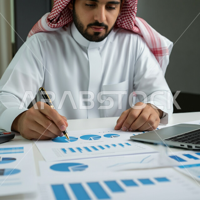قسم التحليلات والإحصائيات البيانية، تطوير استراتيجية العمل وخطة النمو، الاستثمار المالي والاقتصادي، صورة مقربة لرجل عربي خليجي سعودي يرتدي الثوب التقليدي والشماغ يستخدم الحاسوب المحمول، استخدام الأجهزة والتقنيات الحديثة، مراقبة الاقتصاد والمعلومات المالية