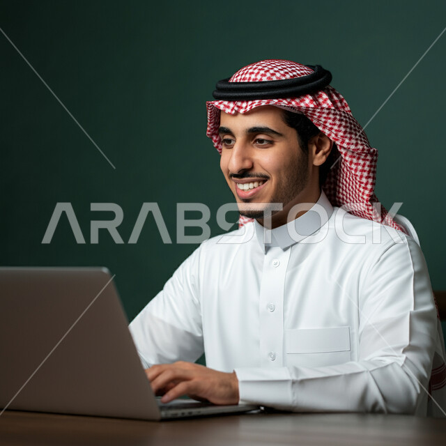 Using modern technology devices, managing and organizing business affairs, close-up portrait of a Saudi Arabian Gulf man wearing a traditional shemagh and thobe working on a laptop, administrative professions and jobs, concept of completing projects and tasks, remote work, green background
