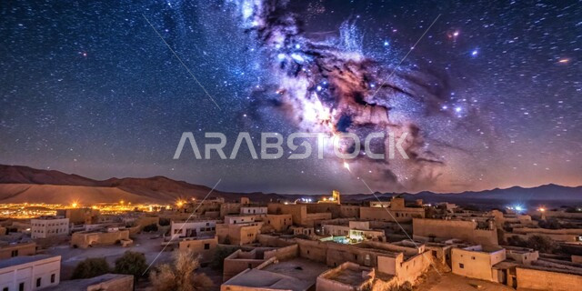 منظر السماء المضاءة بالنجوم اللامعة والأجرام الكونية، مشهد لمجرة درب التبانة والظواهر الطبيعية فوق قرية في الصحراء ليلا، البيوت المصنوعة من الطوب والحجارة على الطراز التقليدي القديم 