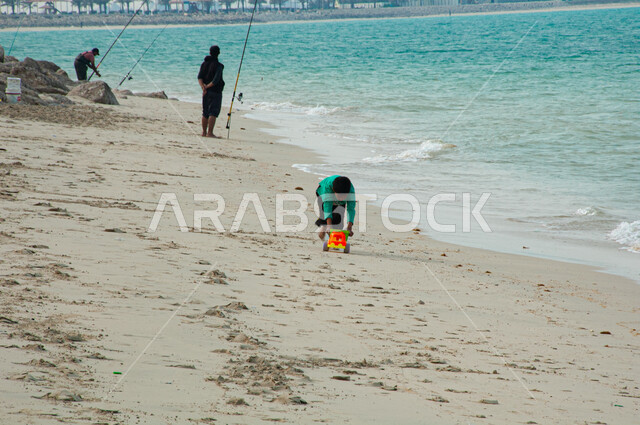 Recreational activities on the Gulf beaches, enjoying the natural scenery and fishing, a Saudi Arabian Gulf boy playing on the soft sand at Ras Tanura Beach in Jubail, marine nature and coastal tourist places, natural rocky coasts in the Kingdom of Saudi Arabia