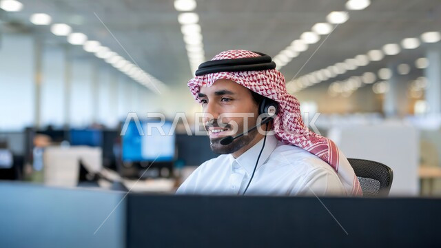 الرد على استفسارات العملاء, استخدام تقنية الهيدفون, صورة مقربة لرجل عربي خليجي سعودي يرتدي الثوب التقليدي والشماغ يعمل في مجال خدمة العملاء والدعم الفني, مهن ووظائف مكتبية سعودية, دمج العمل مع التكنولوجيا الحديثة والمتطورة