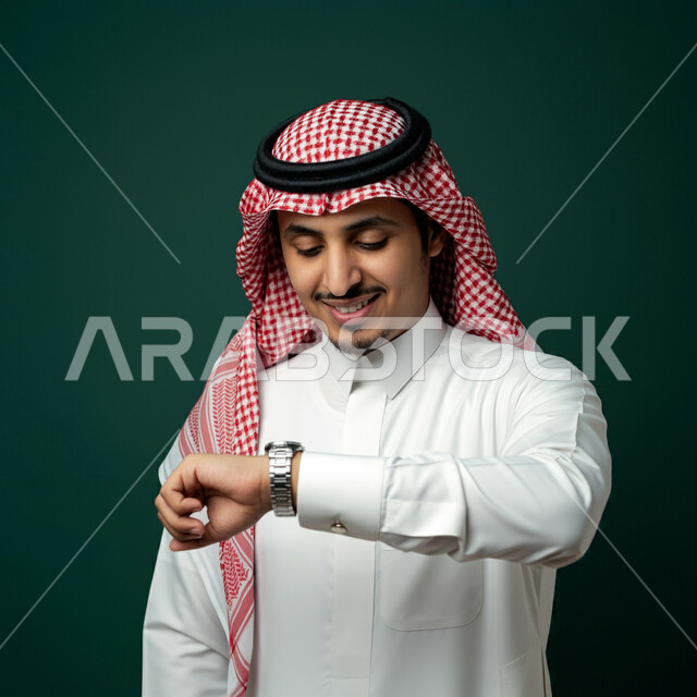 The concept of organizing and managing time, fixed reminders and alerts, the concept of manliness and interest in outward appearance, gestures of looking at the watch and setting appointments, a close-up portrait of a Saudi Arabian Gulf man wearing a traditional shemagh and thobe, wearing a watch on his hand and following it, green background