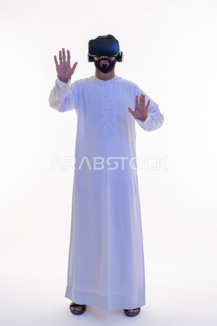 Interaction and simulation of the imaginary world, portrait of an Arab Gulf Emirati man wearing a kandura and virtual reality glasses with self-defense gestures, merging and trying to grab something, modern technologies and technological devices, full-length body image, white background