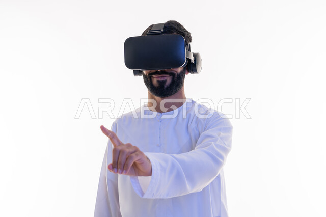 Using the sense of touch to touch holographic elements with tapping gestures, merging, interacting and simulating the imaginary world, close-up portrait of a young Saudi Emirati Arab man wearing a kandura and 3D virtual VR glasses pointing at something with his index finger, white background