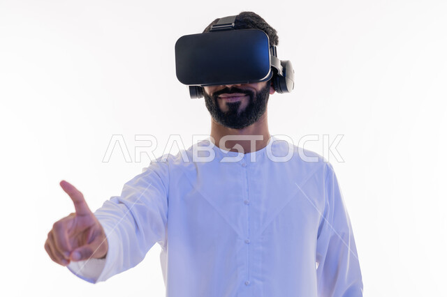 Using the sense of touch to touch holographic elements with tapping gestures, merging, interacting and simulating the imaginary world, close-up portrait of a young Saudi Emirati Arab man wearing a kandura and 3D virtual VR glasses pointing at something with his index finger, white background