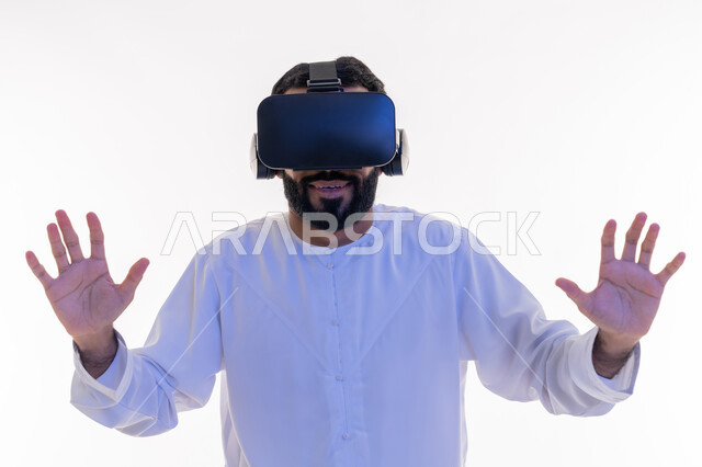 الاندماج ومحاولة امساك شيء ما، التفاعل ومحاكاة العالم الخيالي, بورتريه مقرب لرجل عربي خليجي اماراتي يرتدي الكندورة و نظارات الواقع الافتراضي بايماءات الدفاع عن النفس, تقنيات حديثة وأجهزة تكنولوجية، خلفية بيضاء