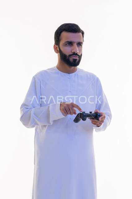 إيماءات الاستمتاع والاندماج والتفاعل, استخدام الأجهزة التكنولوجية والتقنيات الحديثة، بورتريه لرجل عربي خليجي اماراتي يرتدي الكندورة والغترة يقوم بالنقر على عصا التحكم، اللعب بألعاب الفيديو الترفيهية، خلفية بيضاء