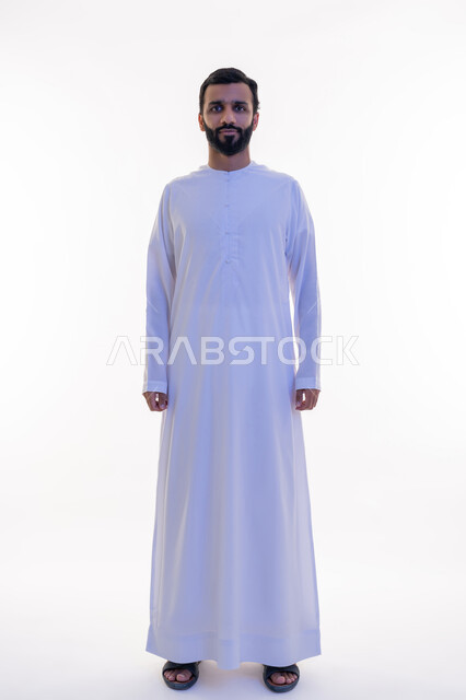 النظر الى الكاميرا بايماءات الثقة بالنفس، الاهتمام بالمظهر الخارجي, مفهوم الأناقة والرجولة, بورتريه لرجل عربي خليجي اماراتي يرتدي الكندورة يقف باستقامة واعتدال، التقاط الصور الشخصية للوثائق الرسمية، الجسم بالطول الكامل، خلفية بيضاء