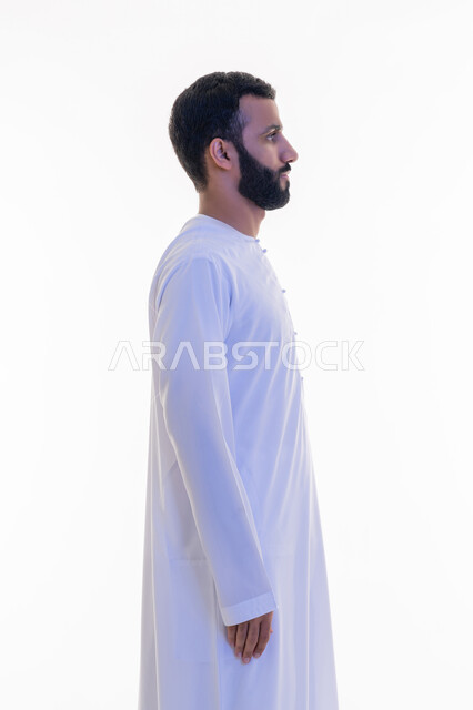 النظر الى مكان ما بايماءات الثقة بالنفس، الاهتمام بالمظهر الخارجي, مفهوم الأناقة والرجولة, بورتريه من الجانب لرجل عربي خليجي اماراتي يرتدي الكندورة يقف باستقامة واعتدال، التقاط الصور الشخصية للوثائق الرسمية، خلفية بيضاء