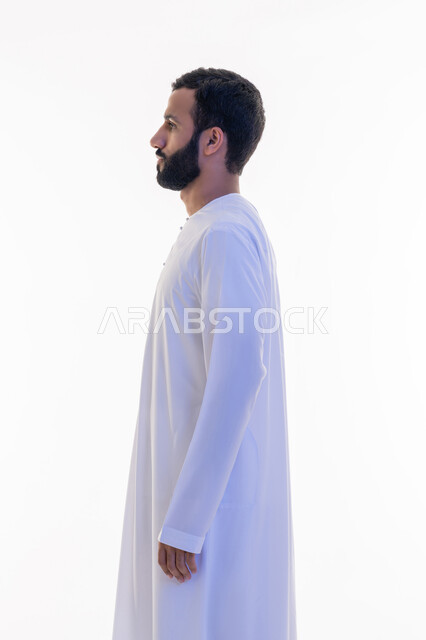 النظر الى مكان ما بايماءات الثقة بالنفس، الاهتمام بالمظهر الخارجي, مفهوم الأناقة والرجولة, بورتريه من الجانب لرجل عربي خليجي اماراتي يرتدي الكندورة يقف باستقامة واعتدال، التقاط الصور الشخصية للوثائق الرسمية، خلفية بيضاء