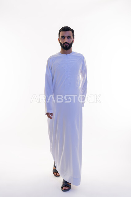 Concern for appearance, gestures of walking and going, looking at the camera with expressions of self-confidence, concept of elegance and masculinity, side portrait of an Arab Gulf Emirati man wearing a kandura, taking personal photos for official documents, full body, white background