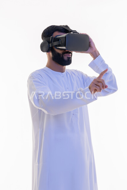 رفع إصبع السبابة للمس عناصر هولوجرلمية، مشاهدة الأفلام باستخدام تقنيات الواقع الافتراضي, محاكاة العالم الخيالي, بورتريه لرجل عربي خليجي إماراتي يرتدي الكندورة يضع نظارة ثلاثية، إيماءات الاندماج والاستمتاع، خلفية بيضاء