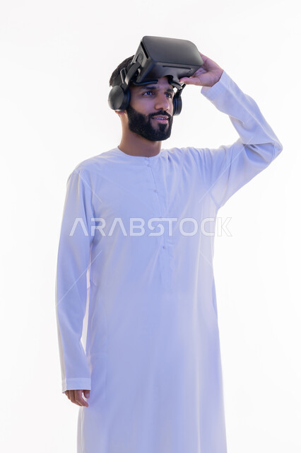 مشاهدة الأفلام باستخدام تقنيات الواقع الافتراضي, بورتريه لرجل عربي خليجي إماراتي يرتدي الكندورة يضع نظارة ثلاثية الأبعاد على رأسه ينظر إلى شيء ما بإيماءات السرور، محاكاة العالم الخيالي، خلفية بيضاء