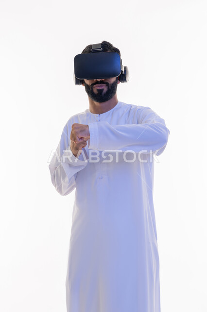 تفريغ الطاقة السلبية، ممارسة رياضة الدفاع عن النفس بتقنيات تكنولوجية، بورتريه لرجل عربي خليجي إماراتي يرتدي الكندورة ونظارات الواقع الافتراضي يرفع يديه بإيماءات الملاكمة والمصارعة، التدرب على الحركات القتالية من خلال ألعاب الفيديو، خلفية بيضاء