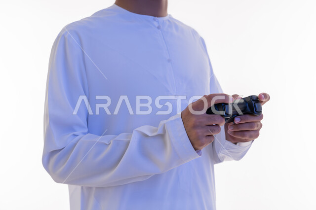 قضاء أوقات الفراغ بلعب ألعاب الفيديو الترفيهية، استخدام الأجهزة التكنولوجية والتقنيات الحديثة، بورتريه لرجل عربي خليجي اماراتي يرتدي الكندورة الإماراتية يمسك بيديه عصا التحكم، خلفية بيضاء