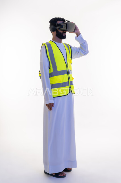 التفاعل مع الهندسة الافتراضية، بورتريه لمهندس عربي خليجي إماراتي يرتدي الكندورة والسترة الخاصة بالعمل ونظارة الواقع الافتراضي يضع يده عليها، دمج التكنولوجيا بالمجالات الهندسية، رؤية مستقبلية 2030، نمو وتطور المجال الهندسي، الجسم بالطول الكامل، خلفية بيضاء