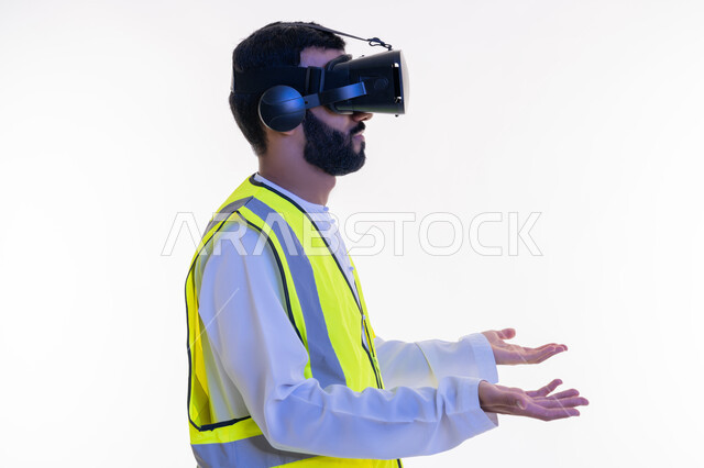 التفاعل مع الهندسة الافتراضية، بورتريه مقرب من الجانب لمهندس عربي خليجي إماراتي يرتدي الكندورة والسترة الخاصة بالعمل ونظارة الواقع الافتراضي يقوم بحمل عنصر ما، رؤية مستقبلية 2030، دمج التكنولوجيا بالمجالات الهندسية، نمو وتطور المجال الهندسي، خلفية بيضاء