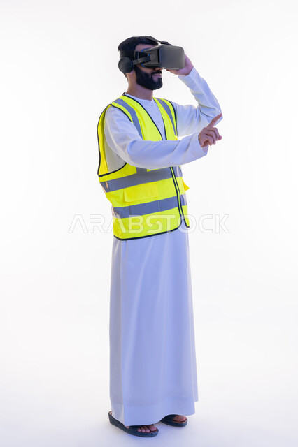 دمج التكنولوجيا بالمجالات الهندسية، التفاعل مع الهندسة الافتراضية، رفع إصبع السبابة للمس عناصر هولوجرلمية، بورتريه لمهندس عربي خليجي إماراتي يرتدي الكندورة والسترة الخاصة بالعمل ونظارة الواقع الافتراضي، رؤية مستقبلية 2030، الجسم بالطول الكامل، خلفية بيضاء