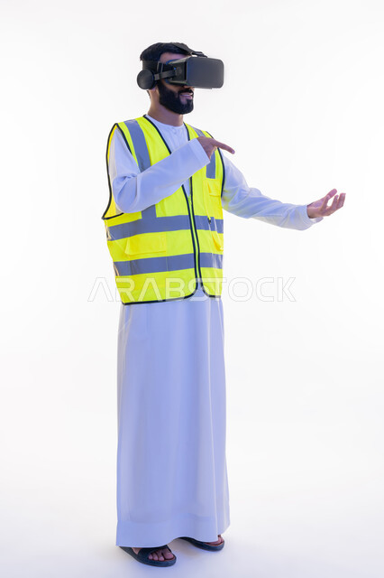 الإشارة بإصبع السبابة إلى عناصر هولوجرلمية في كف اليد، بورتريه لمهندس عربي خليجي إماراتي يرتدي الكندورة والسترة الخاصة بالعمل ونظارة الواقع الافتراضي، رؤية مستقبلية 2030، دمج التكنولوجيا بالمجالات الهندسية، الجسم بالطول الكامل، خلفية بيضاء