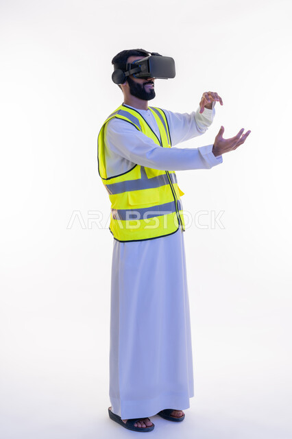 التفاعل مع الهندسة الافتراضية، بورتريه لمهندس عربي خليجي إماراتي يرتدي الكندورة والسترة الخاصة بالعمل ونظارة الواقع الافتراضي يقوم بحمل عنصر ما، دمج التكنولوجيا بالمجالات الهندسية، رؤية مستقبلية 2030، نمو وتطور المجال الهندسي، الجسم بالطول الكامل، خلفية بيضاء