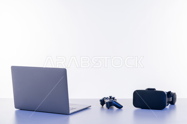 Using modern technology devices, advanced technology in UAE, close-up of desk with virtual reality glasses, joystick and laptop, spending leisure time doing entertaining activities, white background