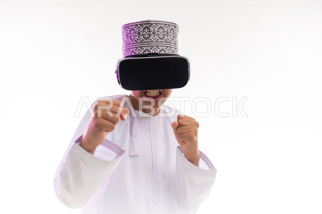 التطور التقني والتكنولوجي, النظر الى الافلام الواقعيه ومحاكاة العالم الخيالي ، المتعة و التسلية بالمشاهدة عبر نظارة الواقع الافتراضي،  بورتريه لولد عربي خليجي عماني يرتدي الدشداشه والكمه ينظر من خلال نظارات ثلاثية الأبعاد (الفي ار)، خلفيه بيضاء