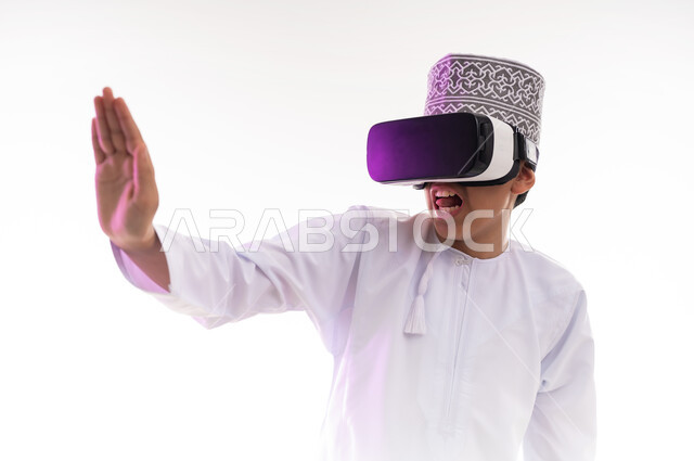 طلب التوقف وعدم الاقتراب, مفهوم الرفض والامتناع، المشاهدة عبر نظارة الواقع الافتراضي،   بورتريه لولد عربي خليجي عماني يرتدي الدشداشه والكمه ينظر من خلال نظارات ثلاثية الأبعاد (الفي ار) يرفع كفه للاعلى بإيماءات النهي عن فعل امر ما, خلفيه بيضاء