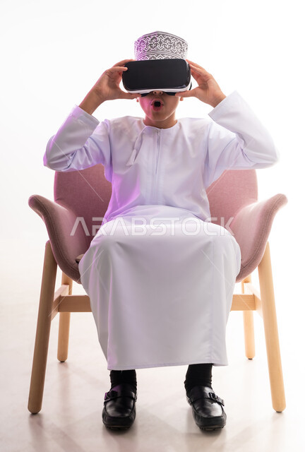 Interaction, integration and focus, simulating the imaginary world and watching real movies, technical and technological development, portrait of an Arab Gulf Omani boy wearing a dishdasha and a kimono, looking through 3D glasses (VR), full-length body, white background