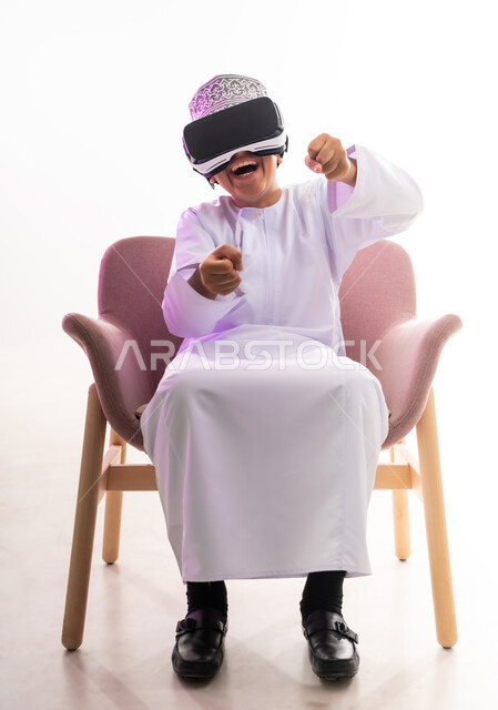 Fun and entertainment by watching through virtual reality glasses, integrating modern techniques and technology, simulating the imaginary world, portrait of an Arab Gulf Omani boy wearing a dishdasha and a cloak looking through 3D glasses (VR), full-length body, white background
