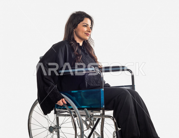 Portrait of a Saudi Arabian Gulf woman, taking a photo session at an angle from the side with different face and hands gestures, seated in a wheelchair, mobility disability, white background, the concept of people with special needs, people of determinati
