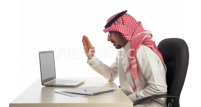 بورتريه لرجل أعمال خليجي سعودي في مقر العمل، إجراء مكالمة فيديو من خلال الحاسوب المحمول لإنجاز المهام، عقد إجتماع عمل عبر الإنترنت، العمل عن بعد، جلسة عمل، مهن وأعمال تجارية، مفهوم إدارة الأعمال، التسويق الإلكتروني، مناقشة إستراتيجية المشروع