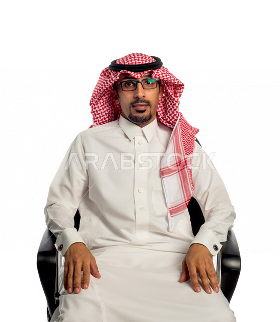بورتريه لرجل عربي خليجي سعودي جالس على كرسي، يقوم بجلسة تصوير، ينظر إلى الكاميرا بإيماءات وجه ويدين مختلفة ، خلفية بيضاء لرجل سعودي مسلم يرتدي زي تقليدي سعودي مع شماغ وعقال