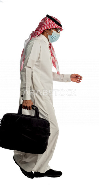 بورتريه لرجل أعمال خليجي سعودي يحمل حقيبة للذهاب إلى العمل بإيماءات وجه ويدين مختلفة، مرتدي القناع الطبي الوقائي للوقاية من فايروس كورونا كوفيد-19، منظر جانبي لرجل سعودي بالزي التقليدي السعودي، إتباع إجراءات الوقاية من الفايروسات، الحفاظ على المسافات